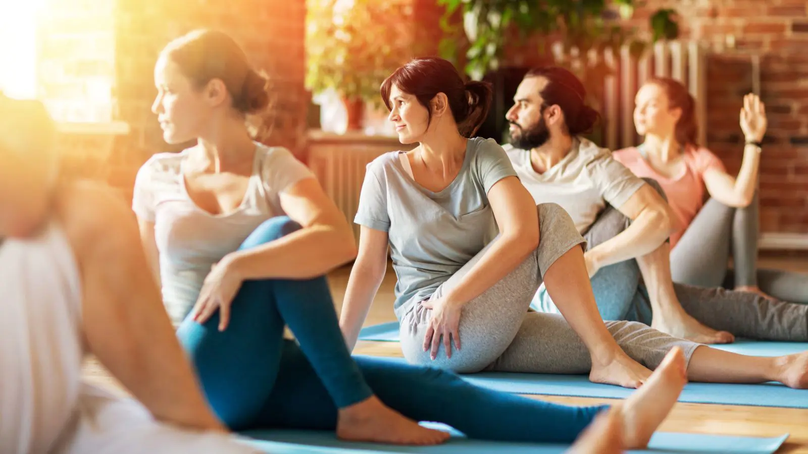 fitness, sport and healthy lifestyle concept - group of people doing yoga seated spinal twist pose in gym or studio